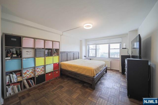 2100 Linwood Avenue, Unit 17T Fort Lee, NJ 07024 - Photo 13 of 17 a bedroom with a bed a dresser and floor to ceiling window