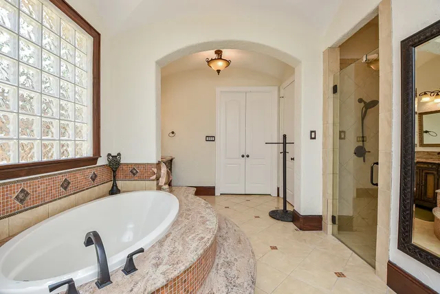 a spacious bathroom with a tub sink and mirror