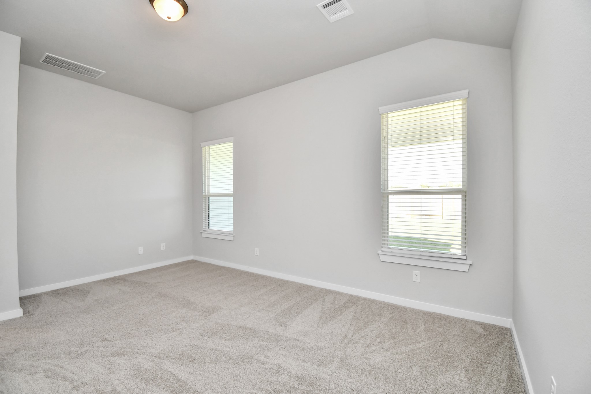 14823 Surfbird Lane Houston, TX 77049 - Photo 19 of 45 Escape and relax in the exquisite primary suite, a haven to unwind after a long day. The spacious room, boasts plush carpeting, soothing paint tones, high ceilings, and expansive windows adorned with privacy blinds.