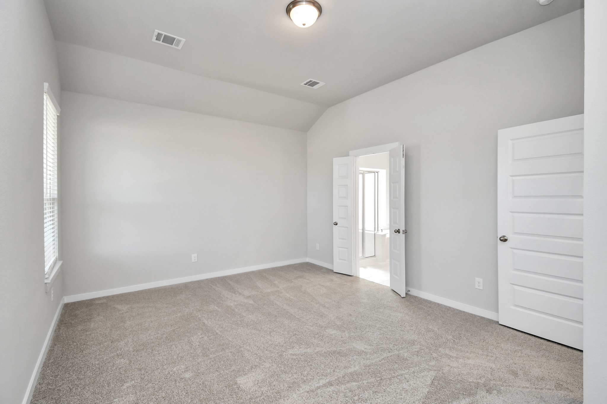 14823 Surfbird Lane Houston, TX 77049 - Photo 22 of 45 Relax and rejuvenate in the luxurious primary suite after a hectic day! This expansive space boasts cozy carpeting, inviting paint tones, lofty ceilings, and sizable windows adorned with privacy blinds.