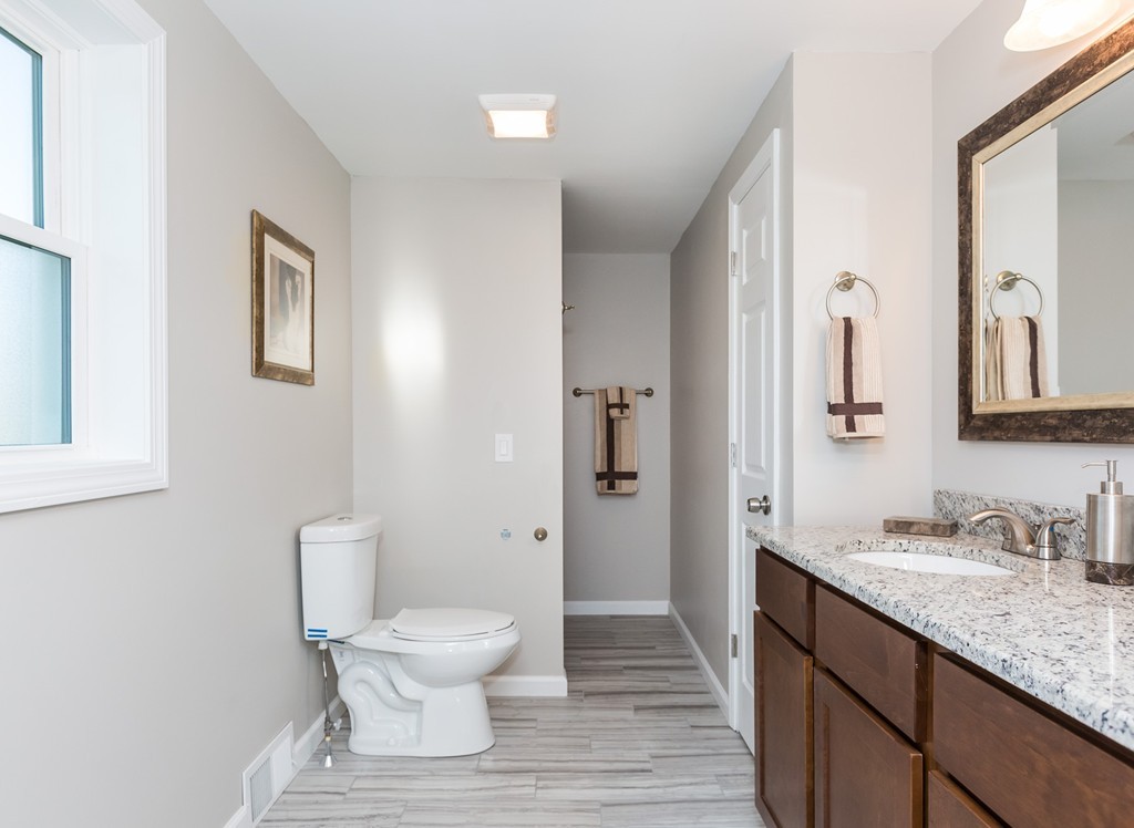 54 Oregon Street Springfield, MA 01118 - Photo 19 of 30 a bathroom with a granite countertop sink a toilet and a large mirror