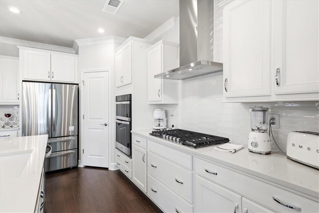2457 Naples Street Hoschton, GA 30548 - Photo 7 of 41 a kitchen with stainless steel appliances a refrigerator a stove and white cabinets