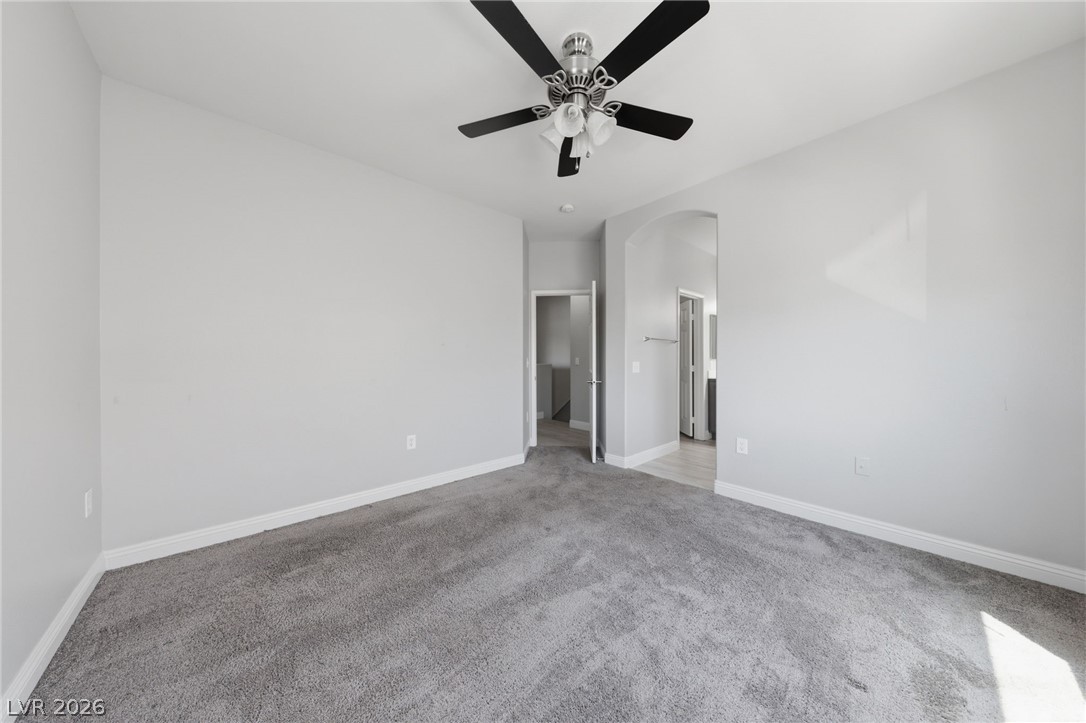 6312 Sandy Ridge Street, Unit 3102 North Las Vegas, NV 89081 - Photo 17 of 31 A spacious bedroom features plush carpet and an elegant ceiling fan.