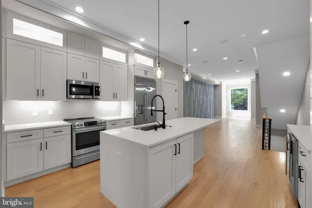 a kitchen with stainless steel appliances granite countertop a sink a stove and a wooden floors