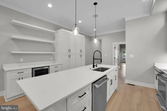 a kitchen with a stove a faucet a chandelier and a view of living room