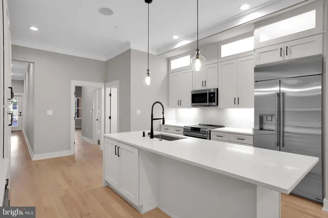 a kitchen with stainless steel appliances a sink a stove a refrigerator a center island and cabinets