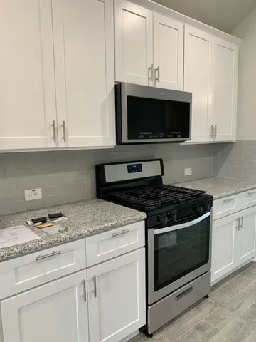 a kitchen with granite countertop a stove a microwave a sink and cabinets