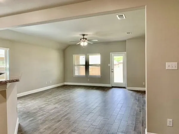 an empty room with wooden floor and windows