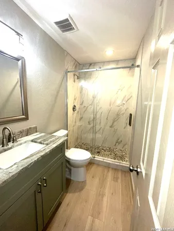 a bathroom with a granite countertop sink toilet and shower