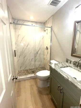 a bathroom with a granite countertop sink toilet a mirror and shower