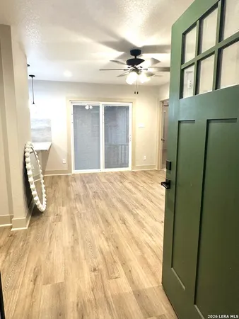 a view of an empty room with wooden floor and a bathroom