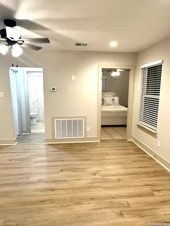a view of empty room with wooden floor and fan
