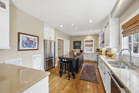 a view of a kitchen with kitchen island a large counter top space a sink stainless steel appliances and cabinets