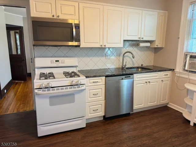 a kitchen with white cabinets stainless steel appliances and wooden floor