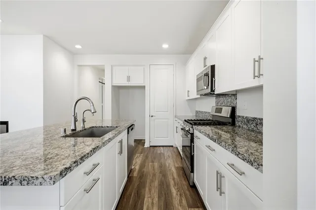 a kitchen with stainless steel appliances granite countertop a sink stove and cabinets