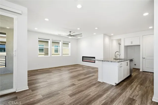 a large kitchen with stainless steel appliances granite countertop a stove a sink dishwasher a refrigerator white cabinets and wooden floor next to a window