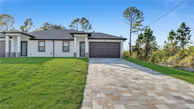 a view of a house with a small yard and a large tree