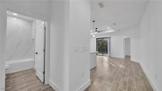 a view of a hallway with wooden floor and a bathroom