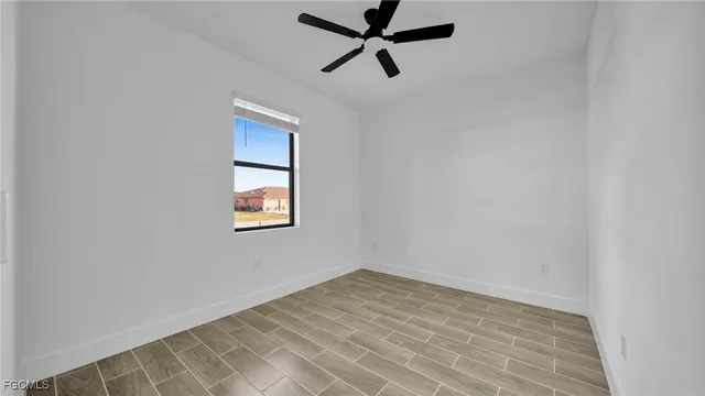 an empty room with a window and a ceiling fan