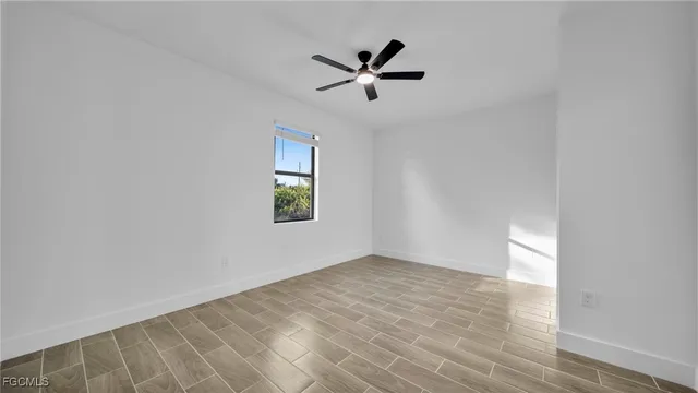 a view of empty room with wooden floor and ceiling fan