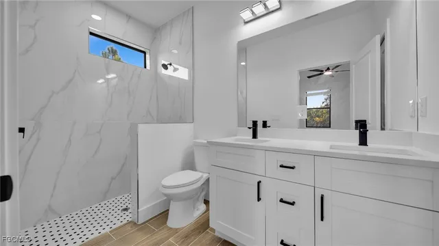 a spacious bathroom with a sink a toilet a shower and a mirror
