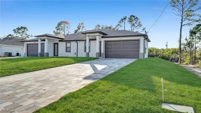 a view of a white house next to a yard with potted plants
