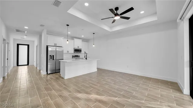 a view of a kitchen with kitchen island stainless steel appliances refrigerator sink and cabinets