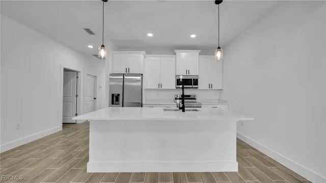 a view of a kitchen with kitchen island a sink stainless steel appliances and cabinets