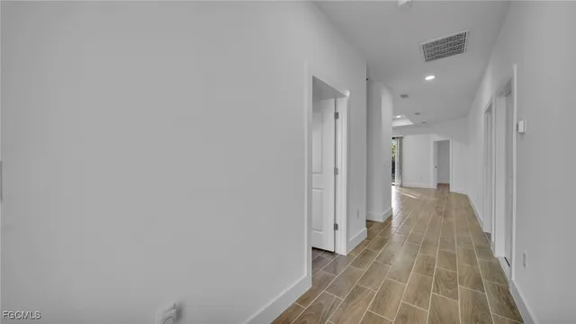 a view of a hallway with wooden floor and a bathroom