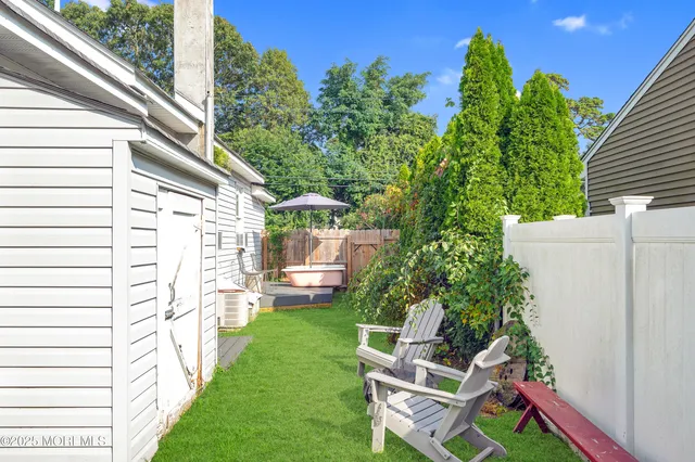 a backyard of a house with table and chairs plants and large tree