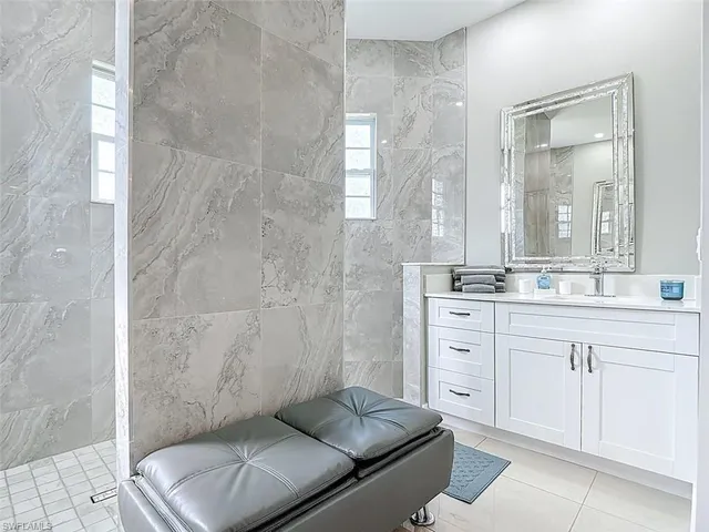 a spacious bathroom with a granite countertop sink a mirror and a bathtub