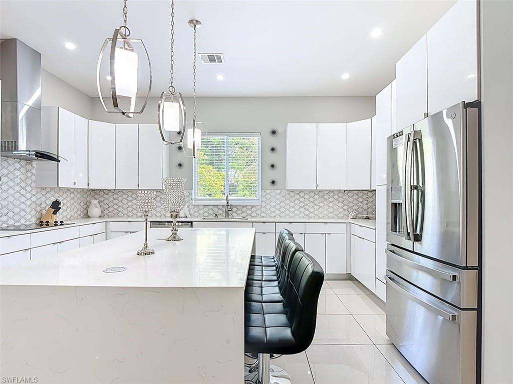 1806 41st Street Southwest Naples, FL 34116 - Photo 17 of 27 a kitchen with stainless steel appliances granite countertop a refrigerator a sink a stove a dining table and chairs with wooden floor