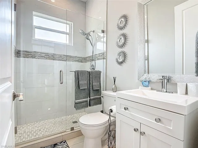 a bathroom with a granite countertop sink a toilet a mirror and shower
