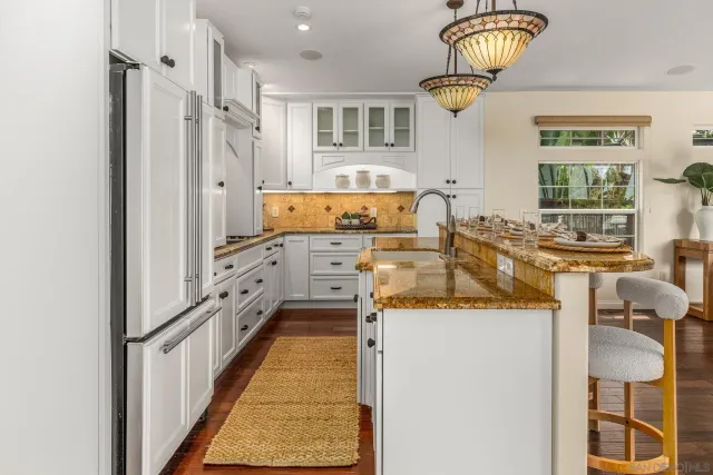 a kitchen with stainless steel appliances granite countertop a sink and a refrigerator