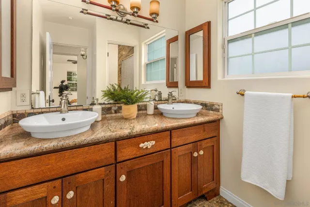 a bathroom with a granite countertop sink and a mirror