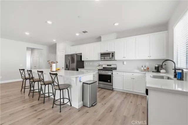 a kitchen with white cabinets a sink dishwasher a stove and a refrigerator with wooden floor