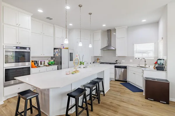 a kitchen with a dining table chairs wooden floor cabinets and appliances