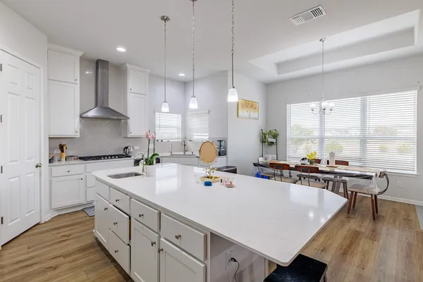 a large white kitchen with a stove a sink dishwasher and a refrigerator with wooden floor