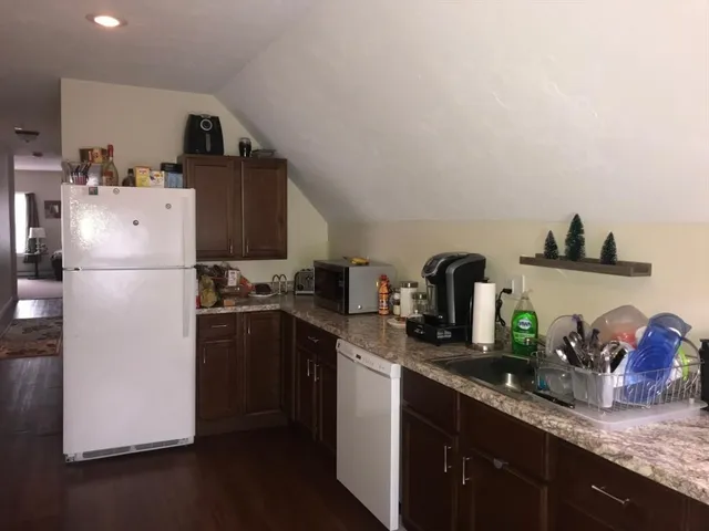 a kitchen with granite countertop a refrigerator a sink and wooden cabinets