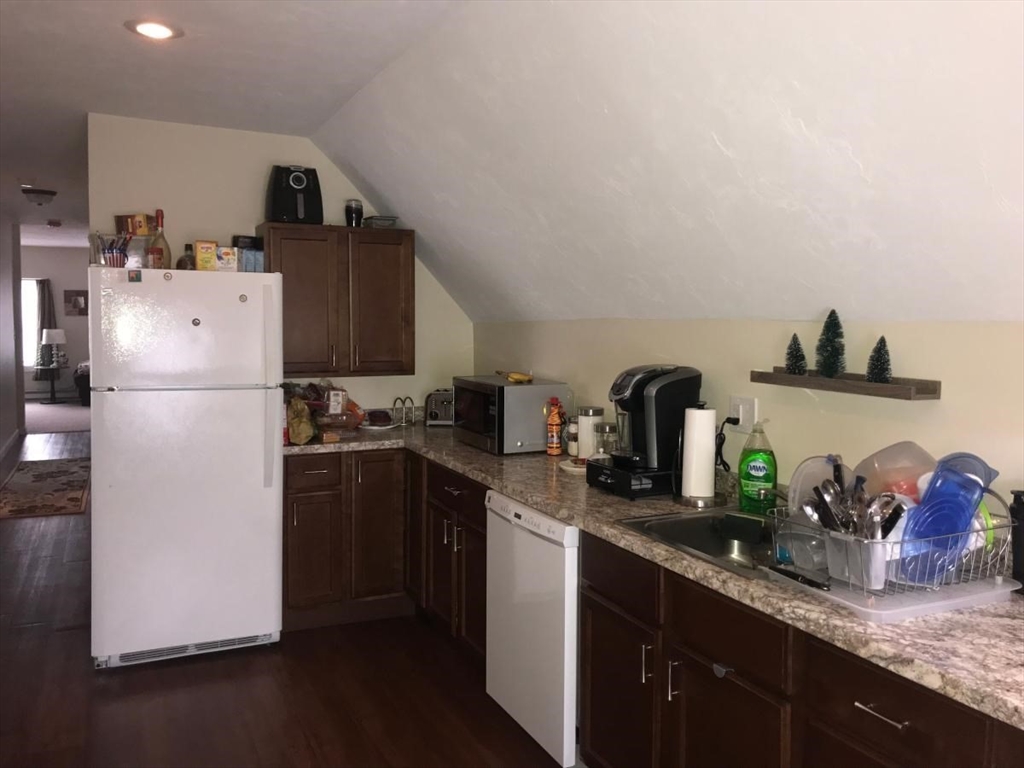 a kitchen with granite countertop a refrigerator a sink and wooden cabinets