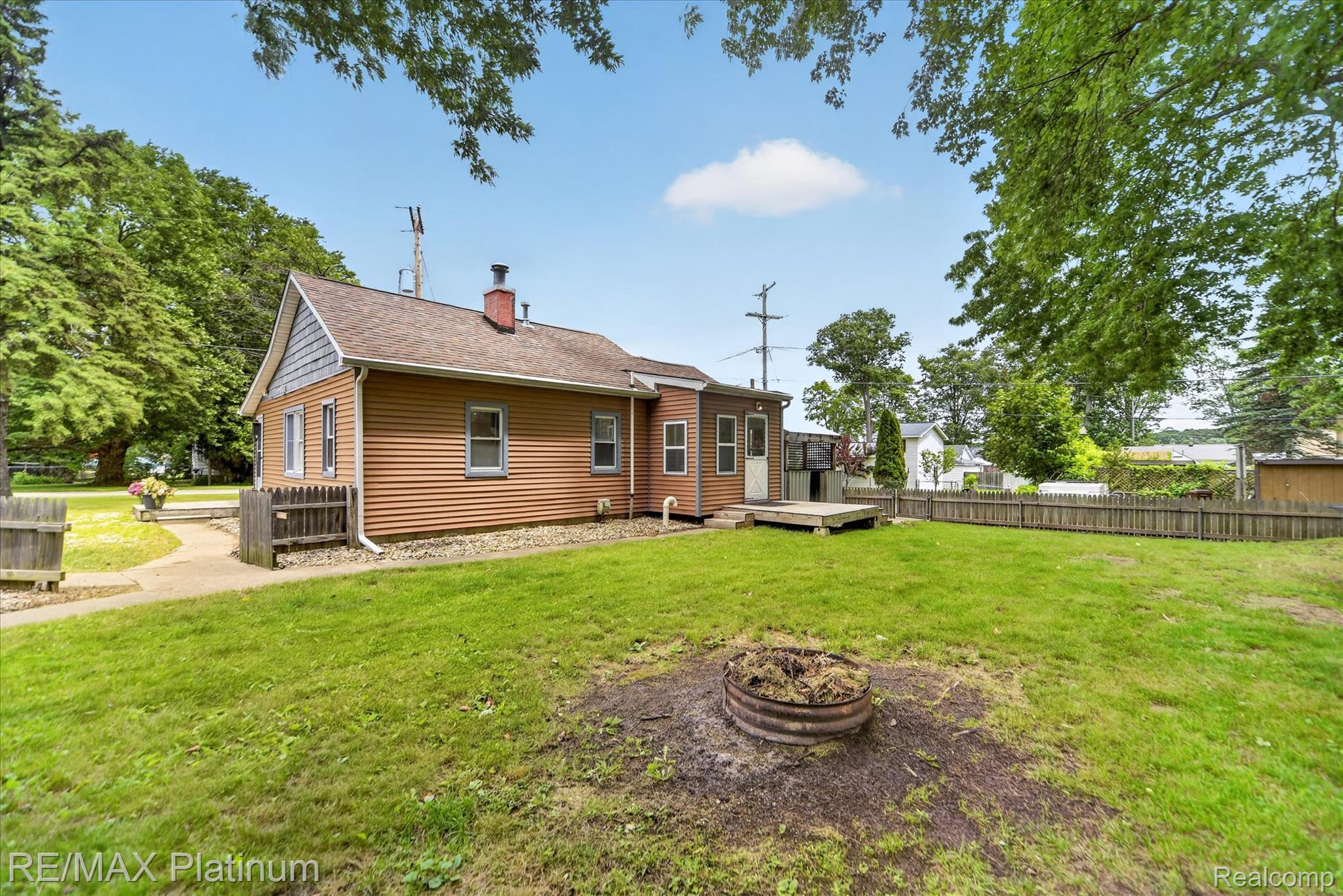501 Kaiser Road Gregory, MI 48137 - Photo 2 of 27 Expansive backyard featuring a lush lawn, a fire pit, and a wooden privacy fence