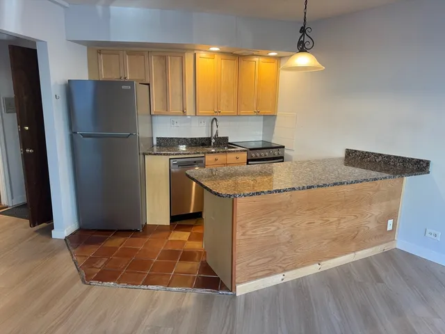 a kitchen with stainless steel appliances granite countertop a refrigerator a stove and a sink