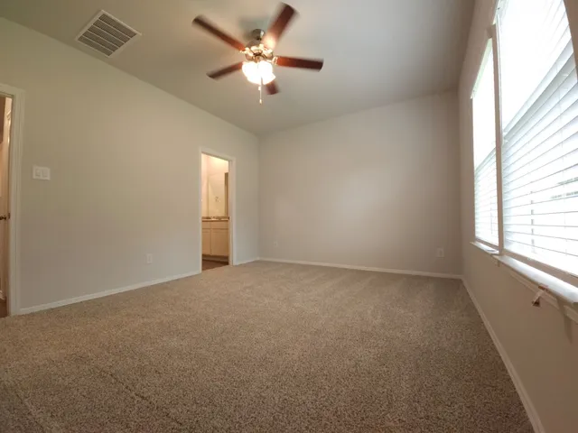 an empty room with a chandelier fan and windows
