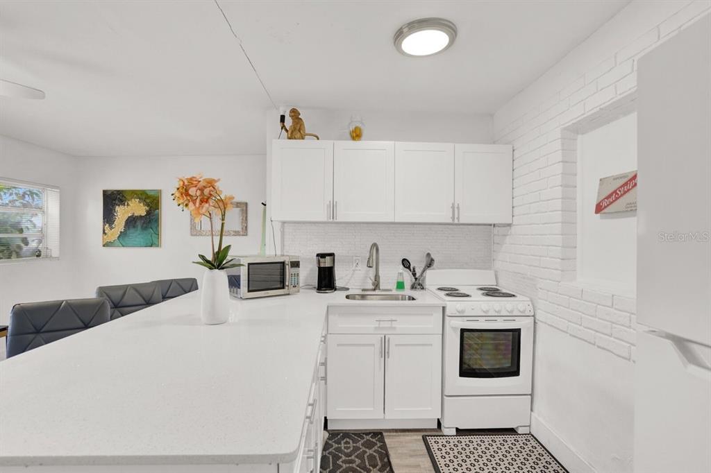 7871 Terrace Road Lantana, FL 33462 - Photo 13 of 19 a living room with stainless steel appliances kitchen island granite countertop a sink and white cabinets