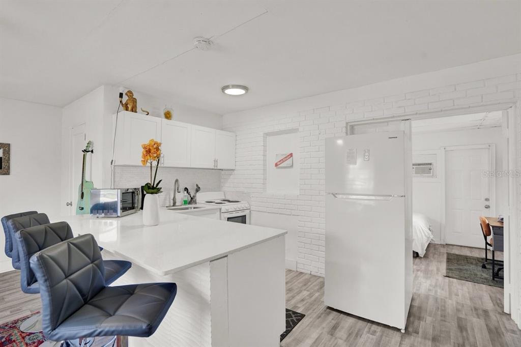 7871 Terrace Road Lantana, FL 33462 - Photo 15 of 19 a kitchen with a refrigerator a stove and a dining table with wooden floor