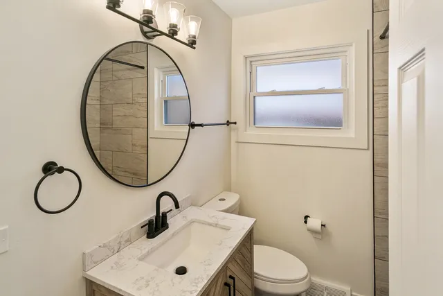 a bathroom with a toilet sink vanity and mirror