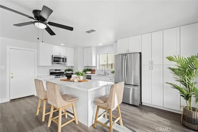 a kitchen with stainless steel appliances a dining table chairs refrigerator and microwave