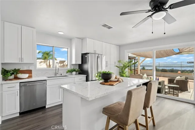 a kitchen with stainless steel appliances kitchen island granite countertop a table chairs in it and wooden floors