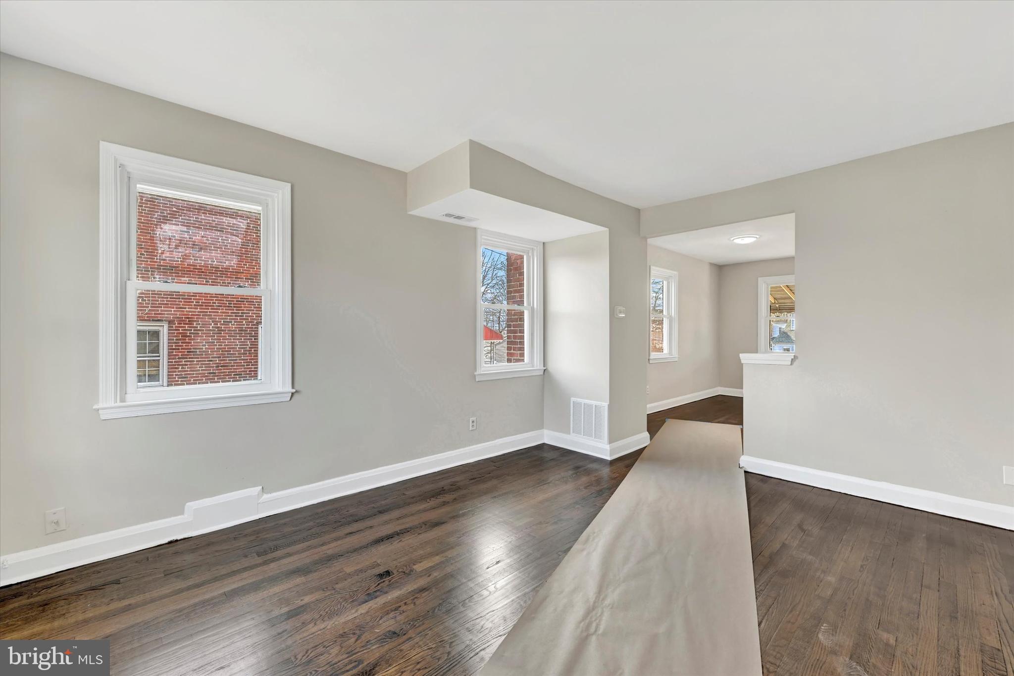 54 Wiltshire Road Essex, MD 21221 - Photo 5 of 22 a view of an empty room with wooden floor and a window