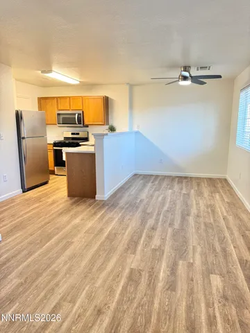 a view of kitchen and empty room with wooden floor